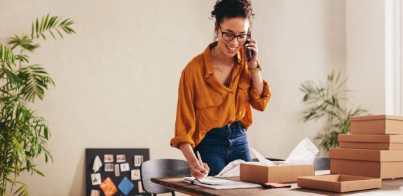 Femme qui parle au téléphone avec des colis GLS à côté d'elle
