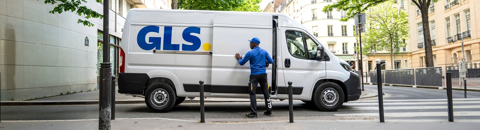 Camion de livraison GLS avec livreur ouvrant la porte latérale lors d’une tournée de distribution de colis en ville.