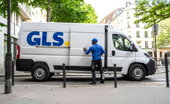 Camion de livraison GLS avec livreur ouvrant la porte latérale lors d’une tournée de distribution de colis en ville.